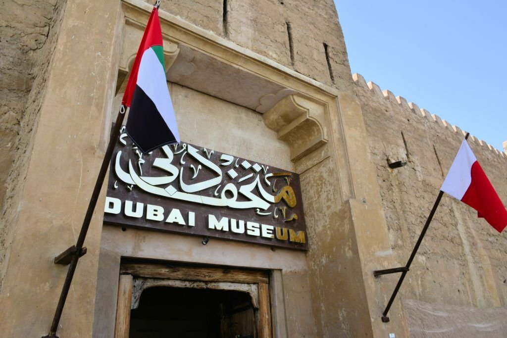 Dubai, United Arab Emirates: Dubai Museum, entrance to Al Fahidi fort, built in 1787 of coral rock, served as the residence of the local rulers until 1896 - flages of the UAE and Dubai - Al Fahidi Historical Neighbourhood also known as Al Bastakiya, Bur Dubai