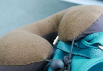 Side view of a brown and gray travel pillow on top of a hand carry luggage, cropped shot